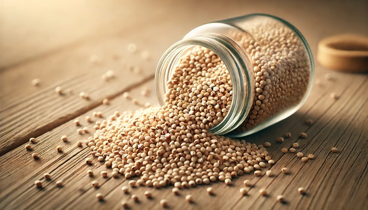 Raw amaranth seeds spilling from a jar onto a wooden table